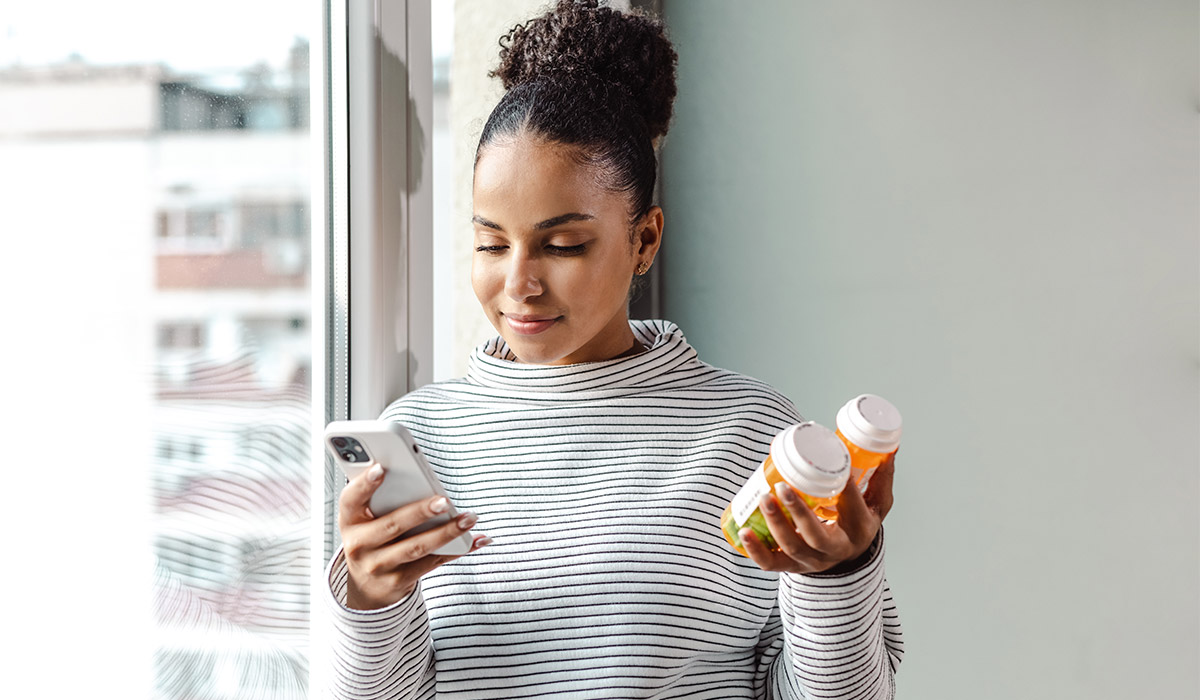 A young woman standing by the window and researching this medicine online